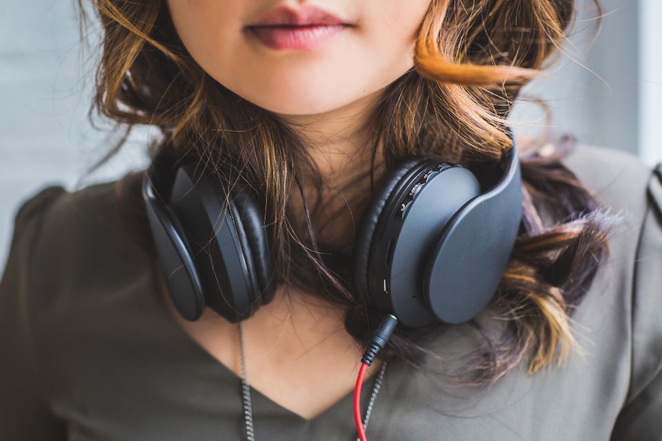 Woman with dark headphones resting around her neck
