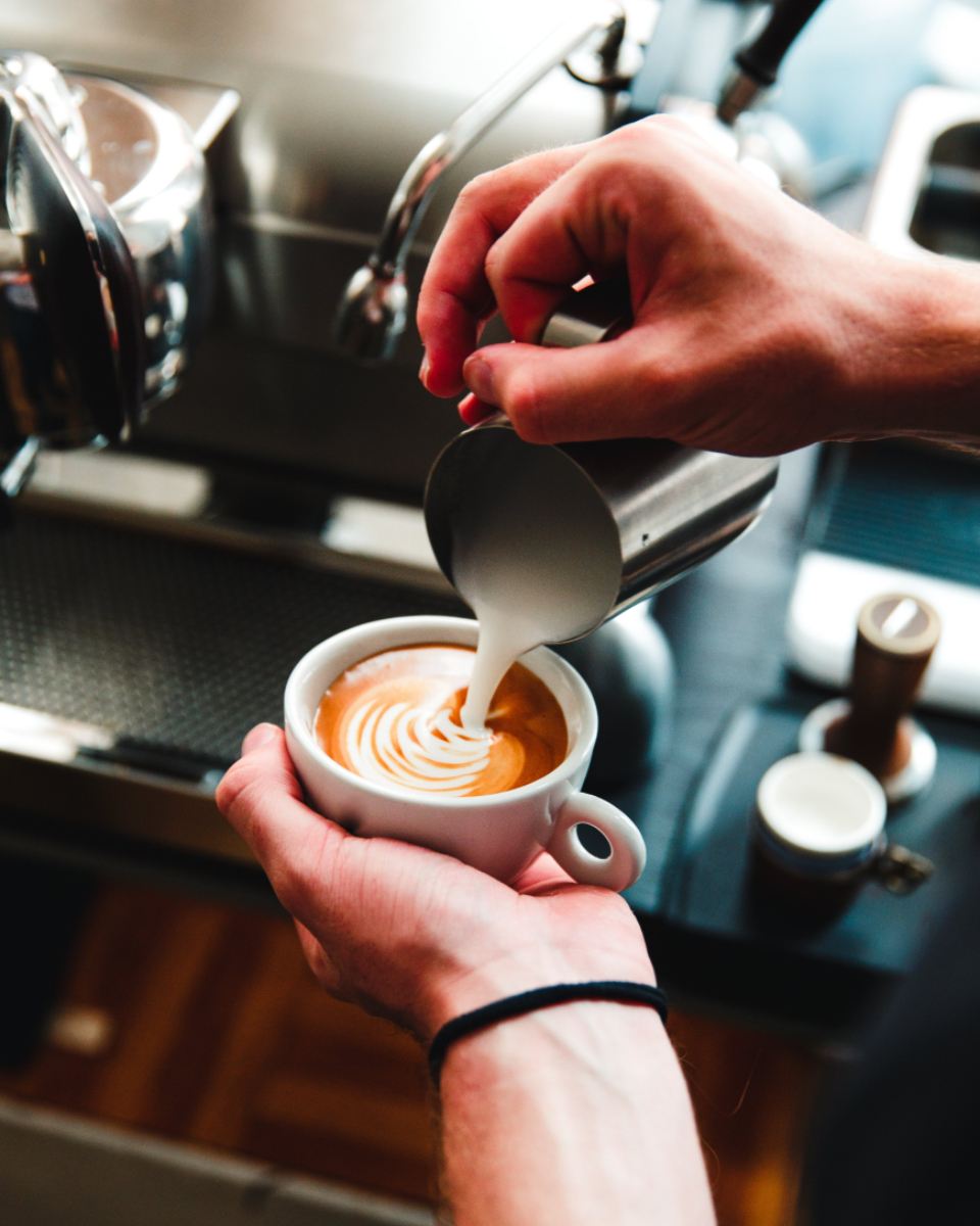 Barista pouring latte art into a cup