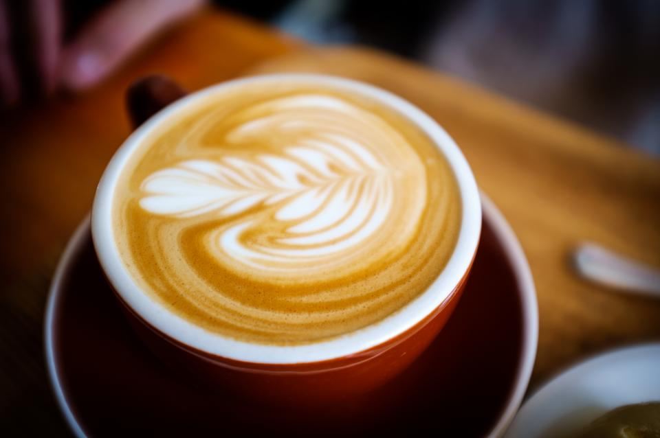 Flat white with leaf latte art in a red cup