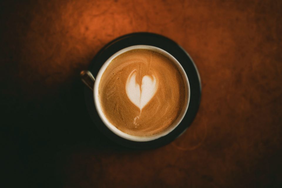 Top-down view of a latte with heart latte art in a dark cup