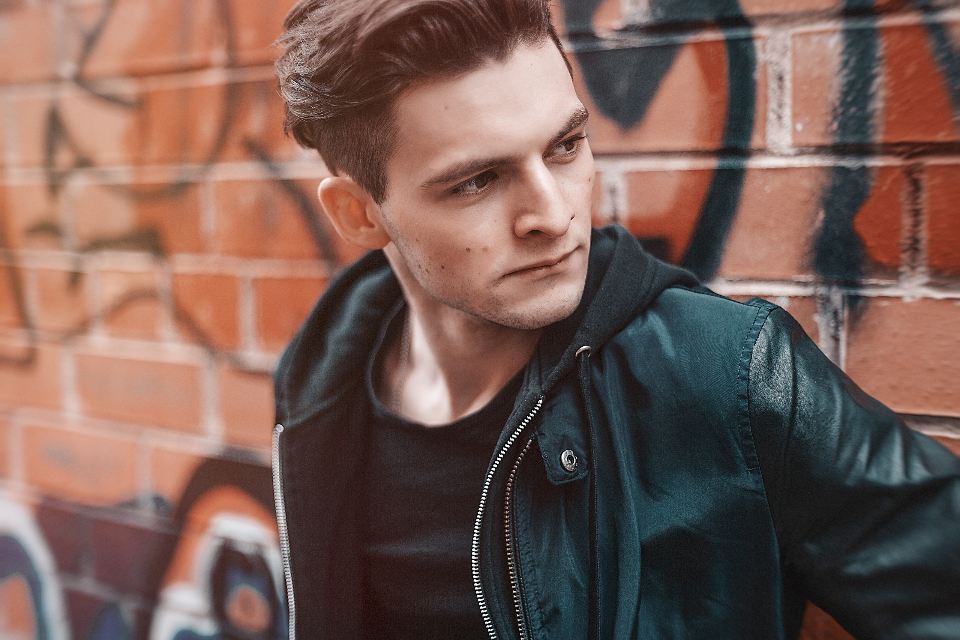 Man in a black leather jacket against a graffiti wall