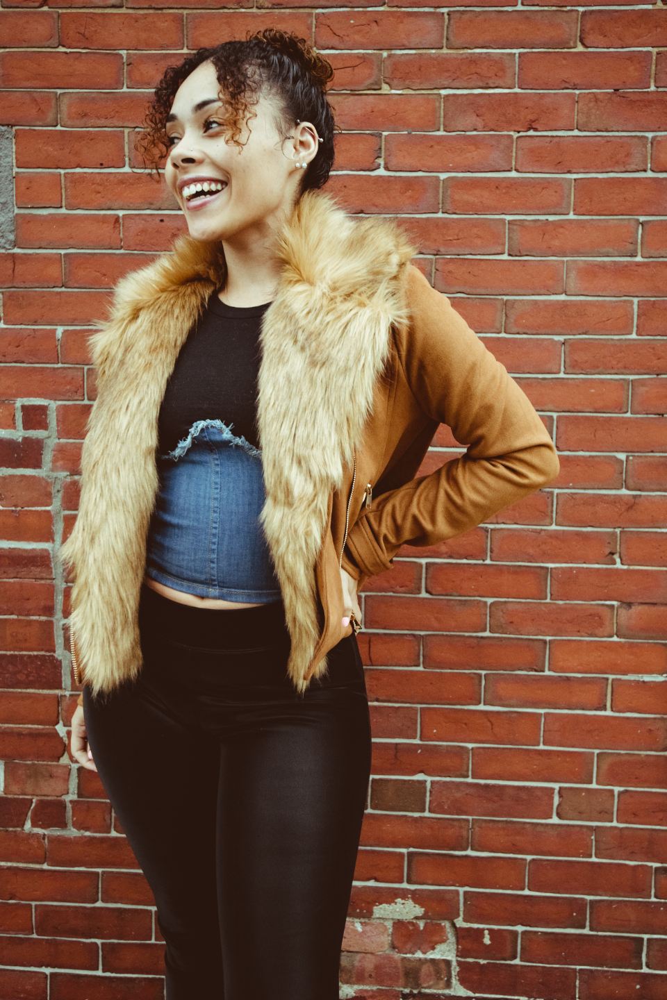 Model in a shearling vest against a brick wall