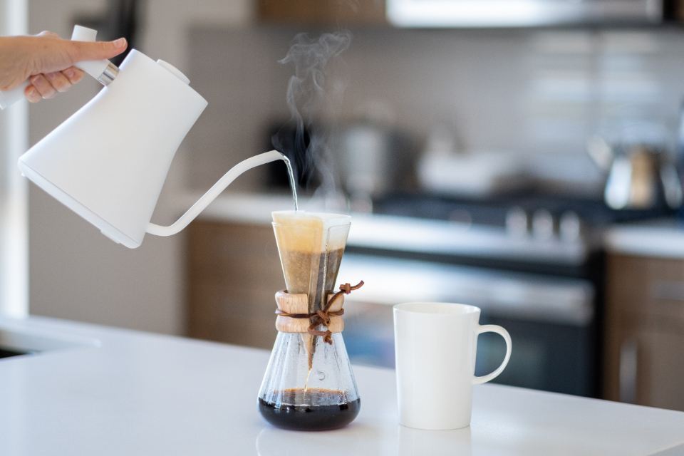 Pour-over coffee being brewed from a white kettle