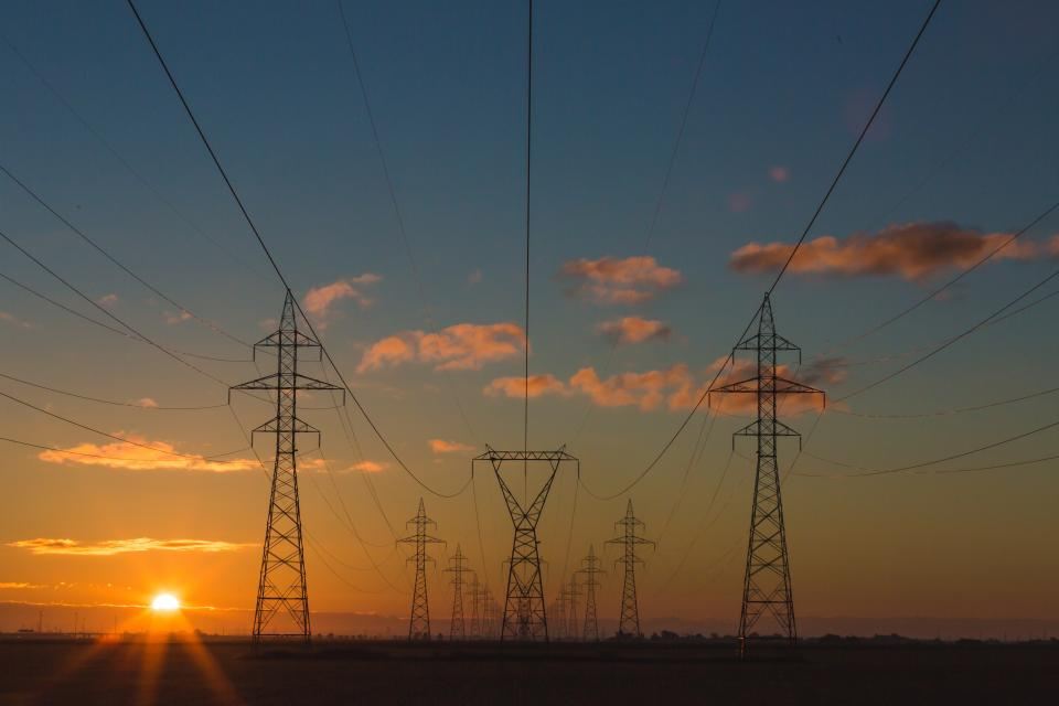Power lines crossing open fields at sunset