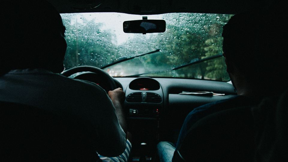 Driver on a rainy road seen from the back seat