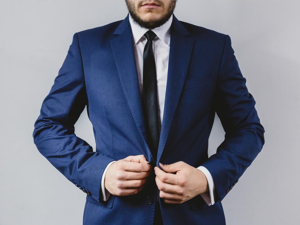 Man buttoning a navy two-piece suit