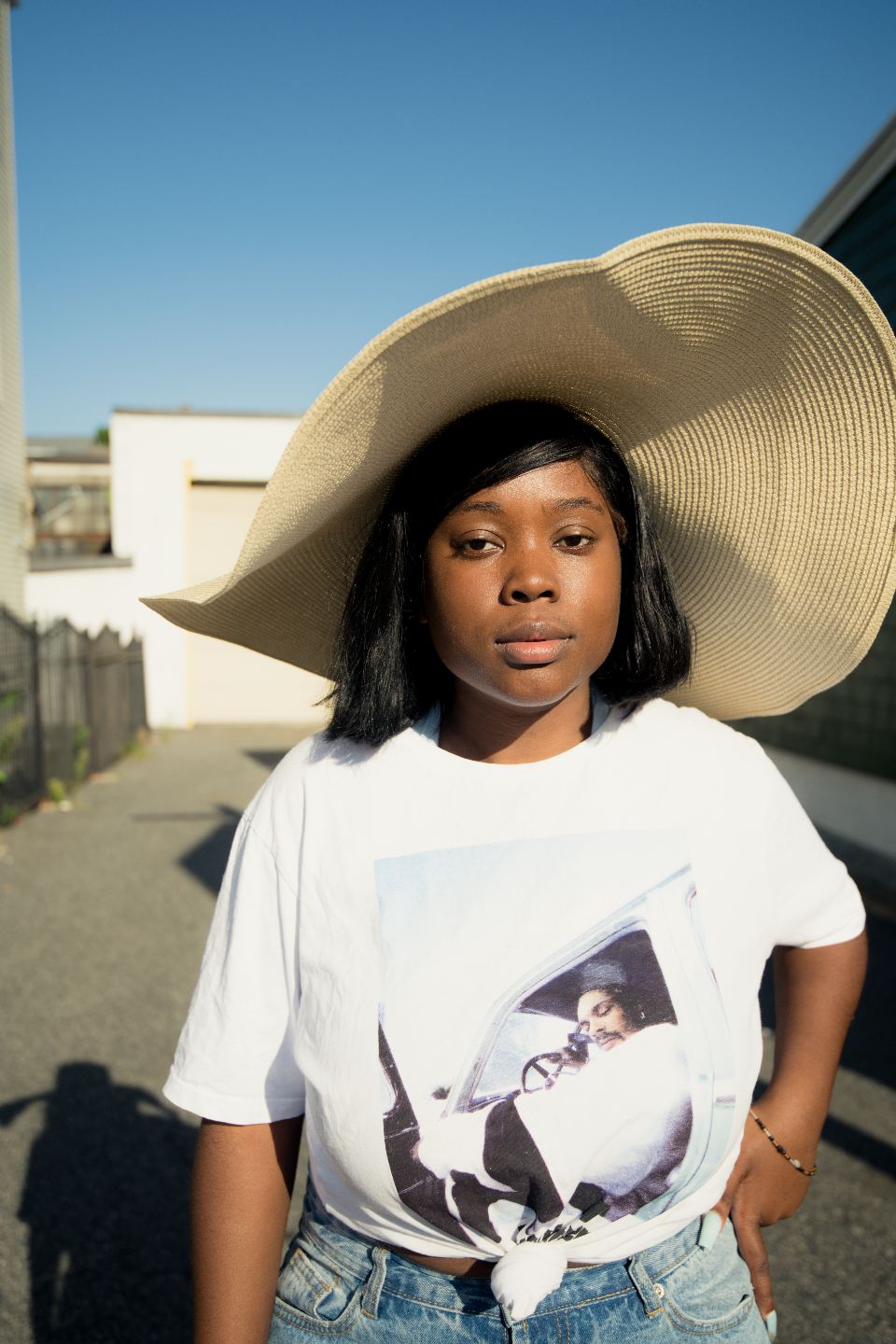 Woman in an oversized straw sun hat and a white printed T-shirt