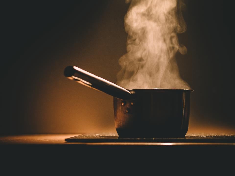 Steam rising from a pot on a dark stove