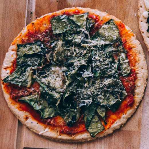 Thin-crust pizza with tomato sauce, wilted spinach and grated cheese, from above
