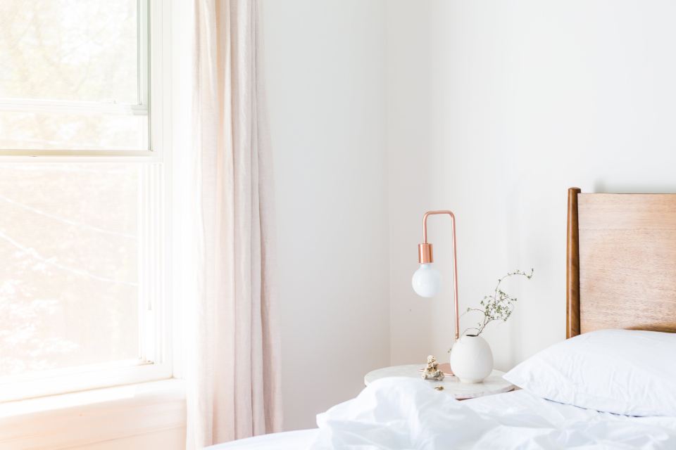 A bright bedroom with white linen and a copper lamp