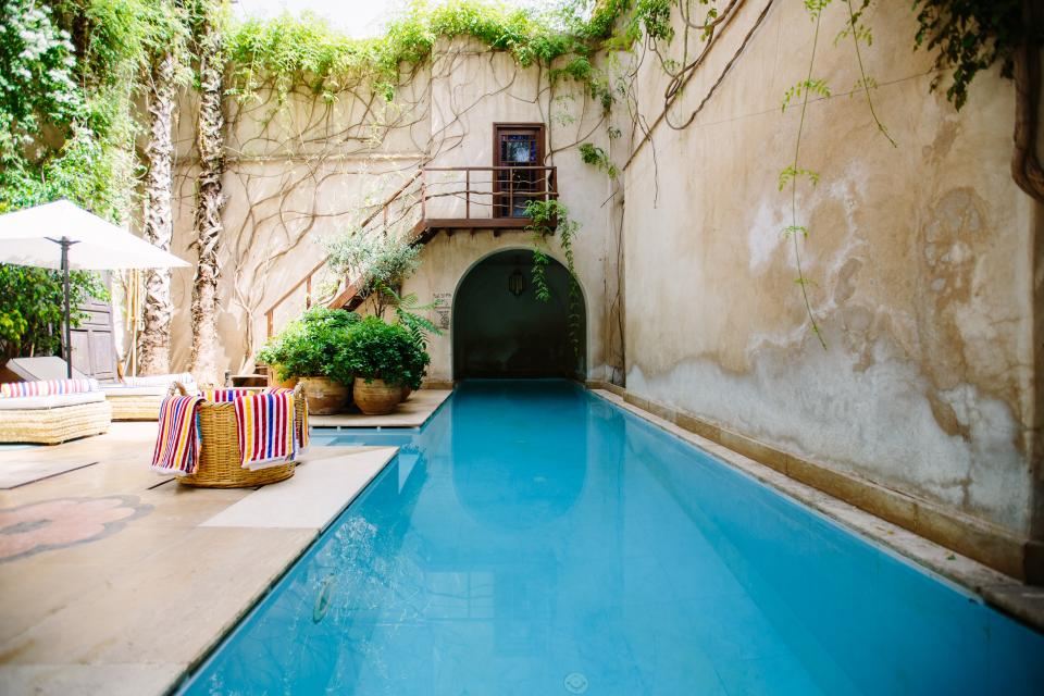 A long courtyard pool between old stone walls and climbing plants