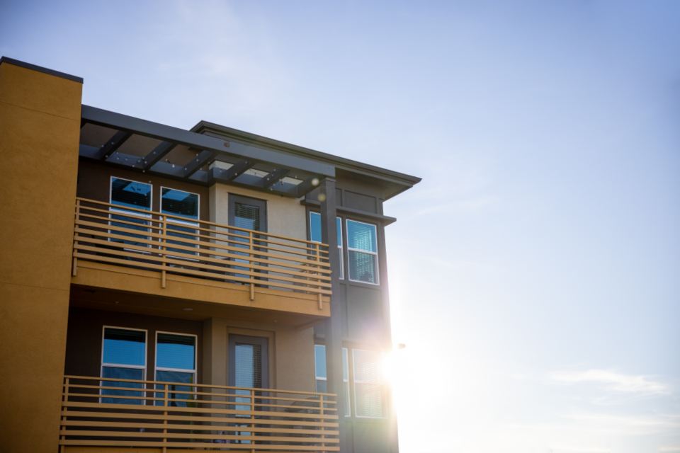 A low-rise apartment building with deep timber balconies in sunlight