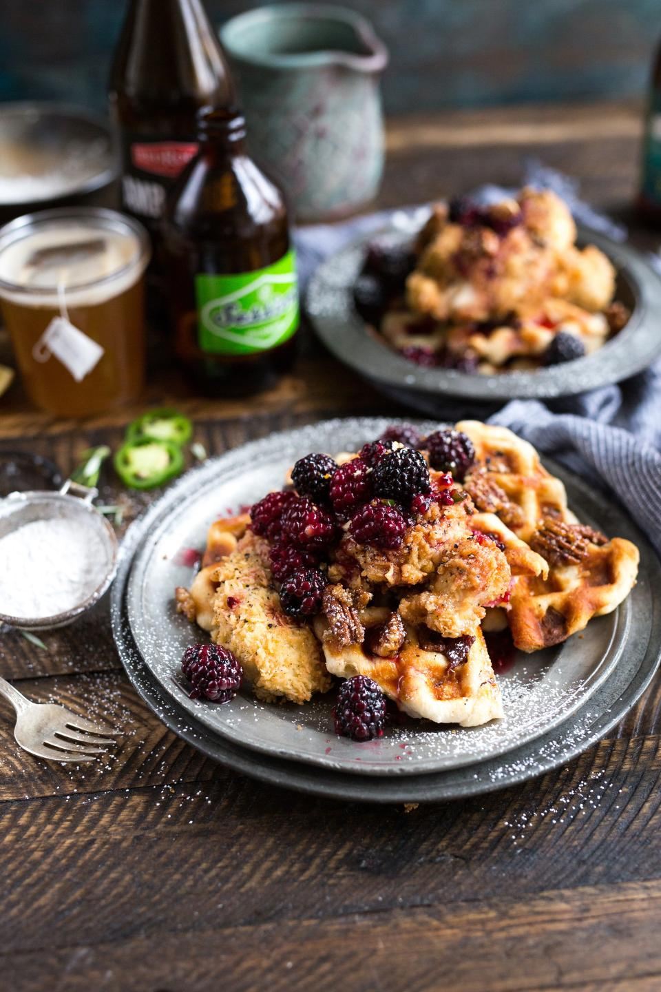 Crisp pancakes topped with blackberries and nuts on a pewter plate