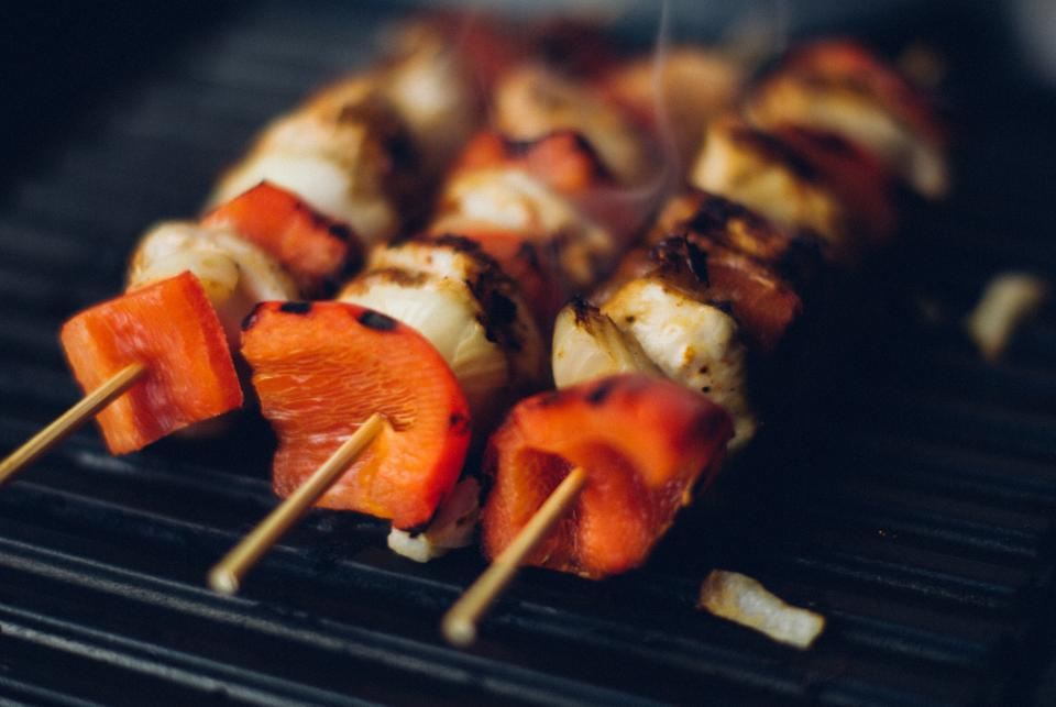 Skewers of charred paneer and red pepper on a grill