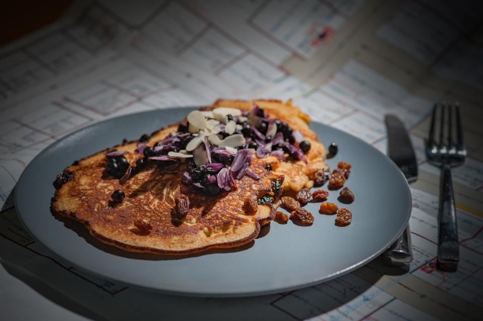 Golden pancake topped with blueberries, raisins and almonds