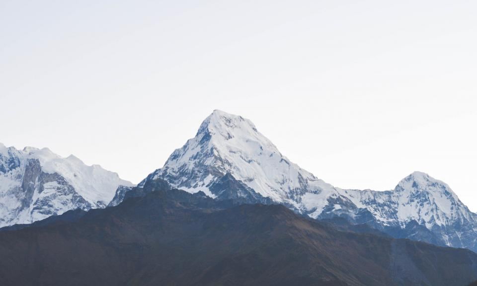 A sharp snow-capped peak rising above green foothills