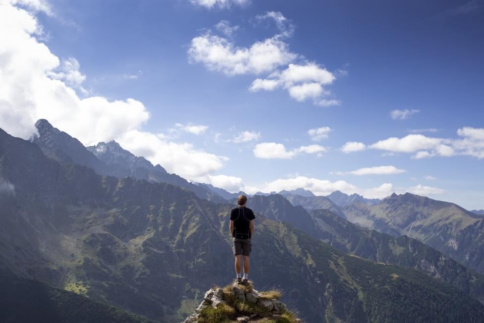 A trekker standing on a summit rock above a valley