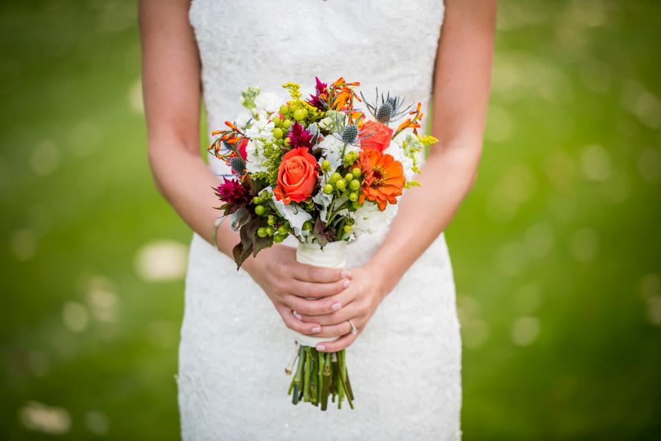 Bride holding a bright orange and red bouquet