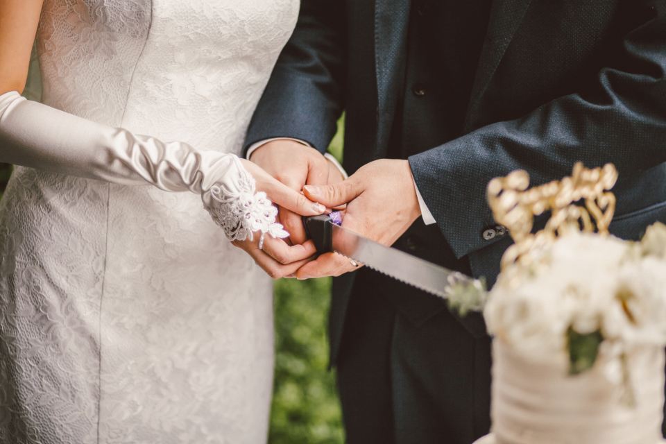 Bride and groom cutting a white wedding cake together
