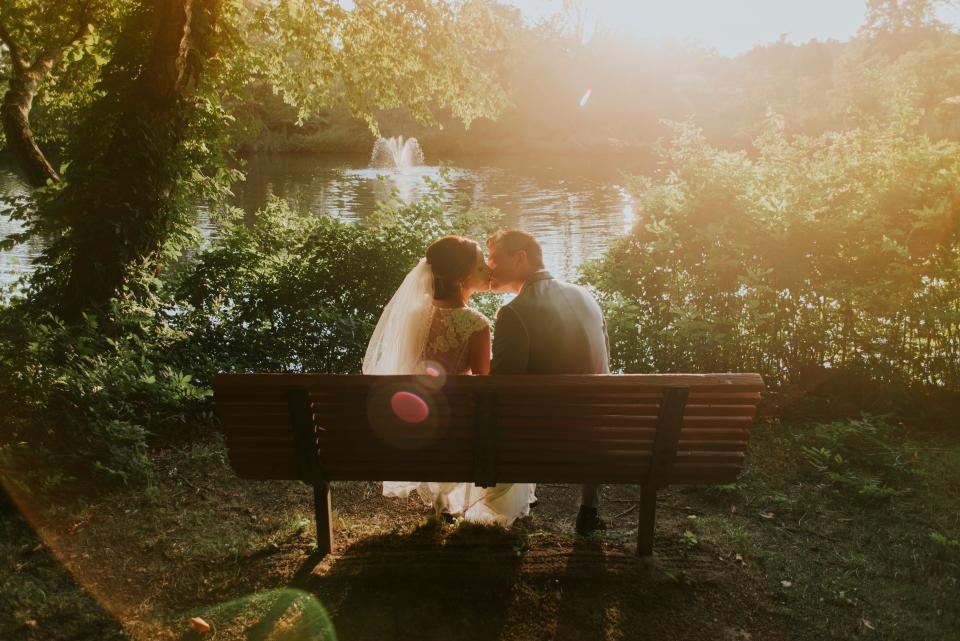 Couple kissing on a bench by a lake at golden hour