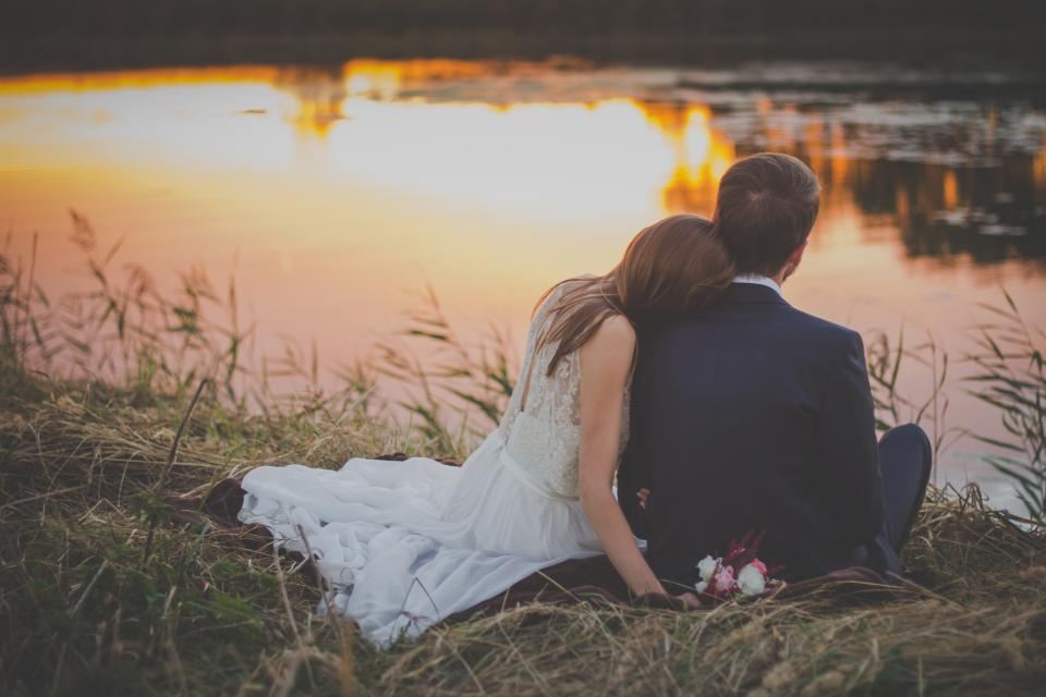 Couple sitting together by a lake at sunset