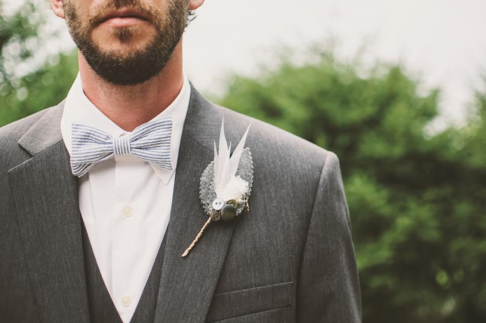 Groom in a grey suit with a bow tie and boutonniere