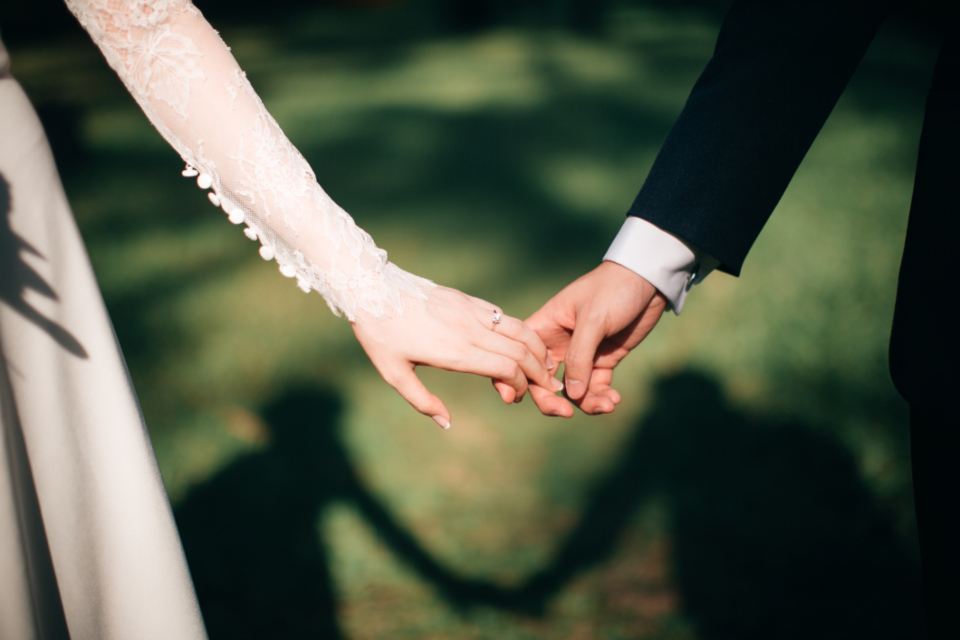 Bride and groom reaching for each other's hands