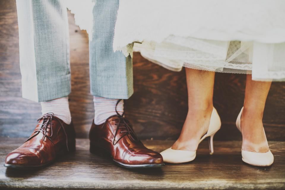 Groom's brown brogues beside the bride's white heels